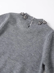 Détail d'un haut en tricot gris avec fleurs en strass et fermeture à col montant