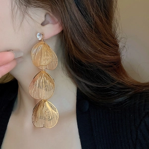 Detailed view of long gold fishtail tassel earrings with layered petals and rhinestones