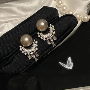 Detailed view of silver crescent earrings with grey pearls and tassel zircons on silk