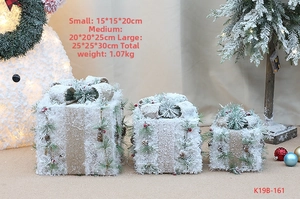 Detailed view of snowy Christmas gift boxes with pine cones and burlap bows
