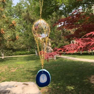 Detailed close-up of a K9 crystal ball suncatcher with a natural blue agate slice pendant