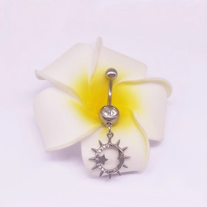 Vue macro d'un piercing nombril argenté avec pendentif soleil et lune sur fleur