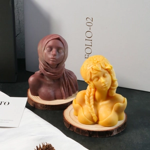 Detailed view of female bust candles in purple and yellow on a wooden base