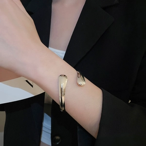 Detailed close-up of polished silver teardrop open cuff bracelet worn on wrist
