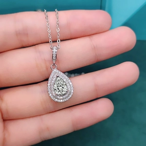 Macro shot of an olive green pear-shaped zircon pendant with a double halo setting
