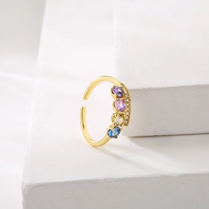 Adjustable gold plated open ring with colorful zircon gemstones on marble display