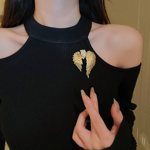 Close-up of sparkling rhinestone angel wing brooch pinned on black knit clothing
