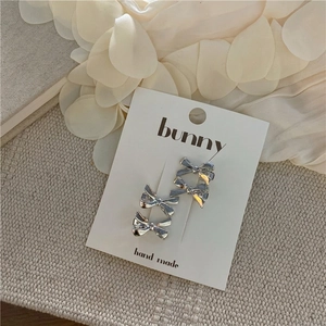 Elegant silver bow hair clips displayed on a handmade card with aesthetic background