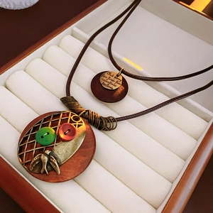 Détail du collier rétro avec breloque oiseau et pendentifs en bois dans un écrin brun