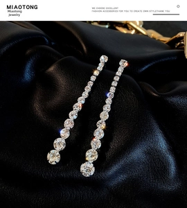 Macro shot of long linear tassel earrings with sparkling white zircons on black leather