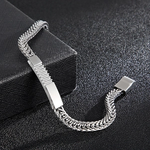 Close-up of silver stainless steel woven chain bracelet with rectangular metal plate