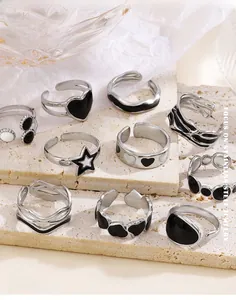 Detail of adjustable stainless steel rings with black enamel hearts and stars