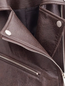 Detail of brown faux leather jacket featuring silver zippers and metallic snap buttons