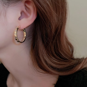 Close-up of elegant gold hoop earrings with colorful zircon heart details on female model
