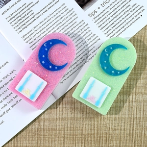Dettaglio di ornamenti in resina rosa e verde con luna, stelle, glitter ed elementi orologio