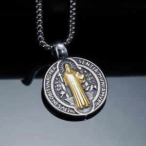 Silver Saint Benedict pendant necklace with golden religious relief on black background