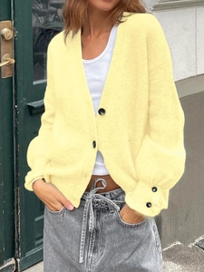 Détail du cardigan en maille jaune douce avec col en V et poignets boutonnés décoratifs
