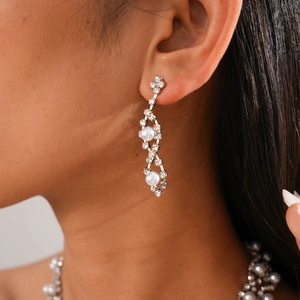 Close-up of model wearing elegant silver drop earrings with crystals and white pearls