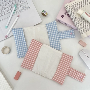 Detailed view of pink and blue plaid fabric book covers with button straps on a desk