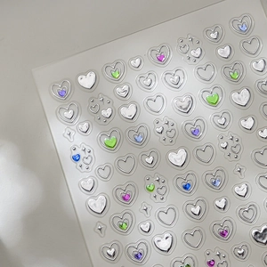 Stickers nail art 5D cœur métallique argent liquide avec gemmes colorées sur fond gris