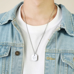 Detailed view of silver rectangular urn pendant with engraved paw print on a chain link