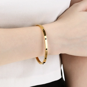Detailed view of a gold-plated stainless steel bangle with black dotted crystal accents