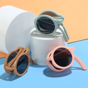 Foldable round kids sunglasses in bean green, coffee, and pink on geometric props