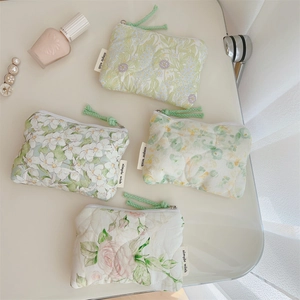 Flat lay of floral quilted mini storage pouches with zippers and woven cord pulls