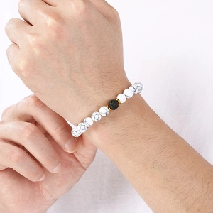 Detail of beaded bracelet with white marble stones and black lava rock on wrist