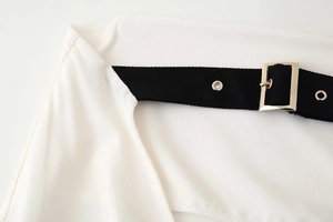 Detail of white fabric texture with a black woven belt and gold rectangular metal buckle