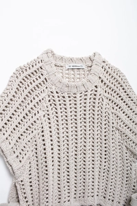 Détail d'un pull en maille épaisse avec motif ajouré blanc crème et étiquette de taille