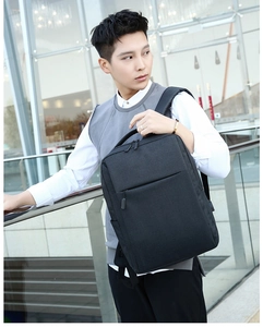 Waterproof laptop backpack shown on model in urban setting with glass architecture