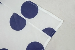 Close-up of white fabric with blue polka dots showing stitching and mesh texture