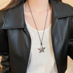 Macro view of leopard print star pendant on black wax cord necklace worn by model