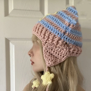 Detail of hand-knitted cat ear hat with pink and blue stripes and yellow star charms