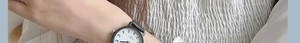 Detailed view of a minimalist quartz watch with white dial and black Arabic numerals on wrist