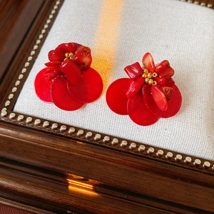 Macro shot of red shell and coral floral earrings on a vintage wooden frame tray