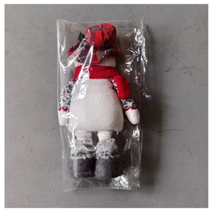 Detail of Christmas snowman plush toy in packaging with red scarf and knitted hat