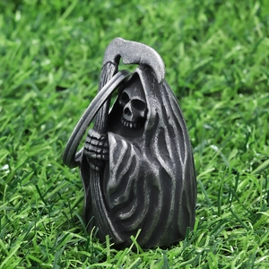 Detailed close-up of a vintage stainless steel Grim Reaper bell pendant on green grass
