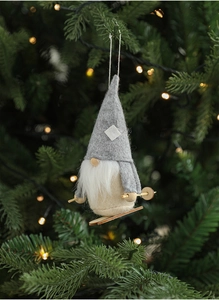 Detail of grey plush Christmas gnome hanging on tree with soft festive lights background