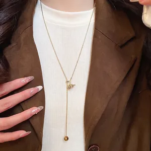 Golden Y-shaped long necklace with tiger eye stone and carved gourd pendant on model
