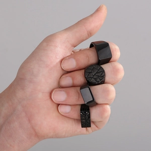 Set of four minimalist black geometric rings in matte finish worn on hand