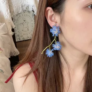 Handmade blue and white oversized floral drop earrings worn on a model for display