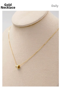 Detailed close-up of a gold cylinder pendant with white zircons on a delicate chain