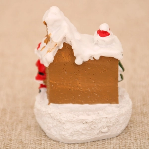 Detail of miniature resin Christmas house with snow-covered roof and red holiday accents