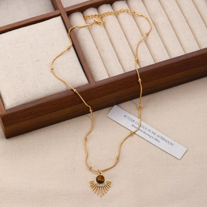 Detail of sunburst pendant with brown tiger eye stone on a golden chain accessory