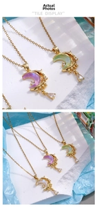 Detailed view of crescent moon pendant with colorful inlay and teardrop crystal charm