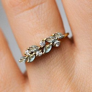 Close-up of golden leaf ring with marquise-cut turquoise stones and white diamonds