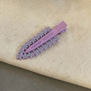 Barrette à cheveux étoile violette mate au fini bonbon sur fond de lin beige chic