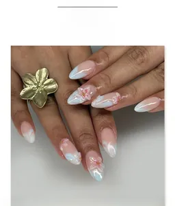 Gros plan d'ongles marbrés bleus avec fleurs blanches et perles sur pointes amandes